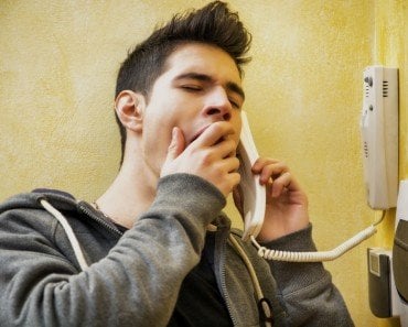 Young man or teenager answering the intercom yawning