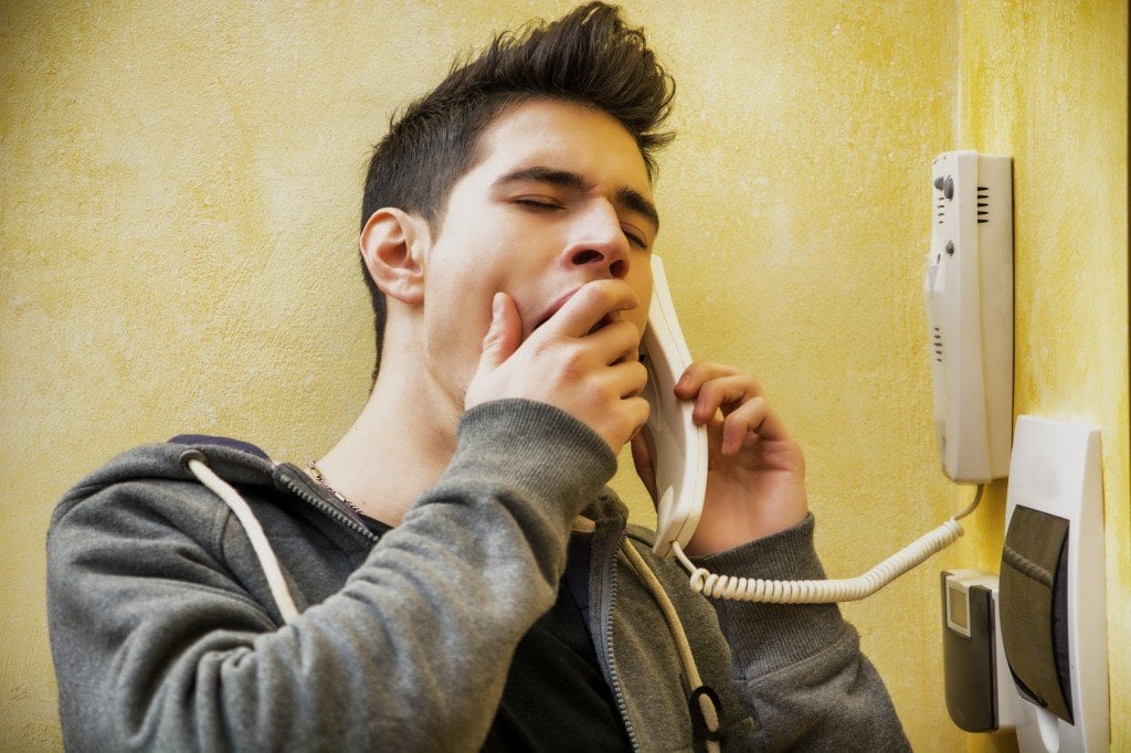 Young man or teenager answering the intercom yawning