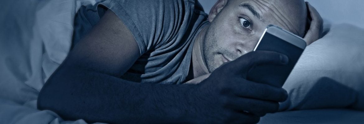internet addict man awake at night in bed with mobile phone