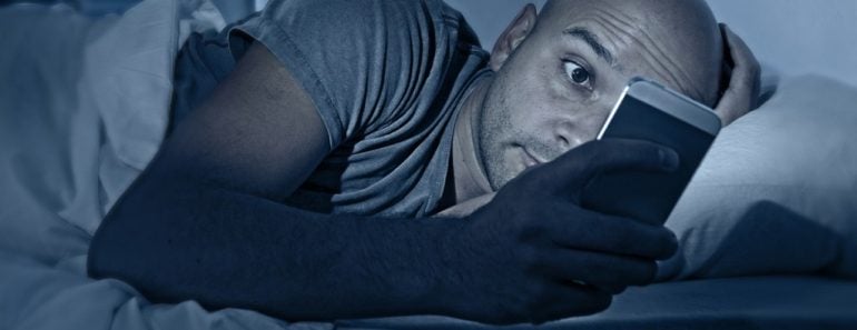 internet addict man awake at night in bed with mobile phone