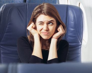 long-haired beautiful young brunette woman covering her ears with her hands, isolated on a white background