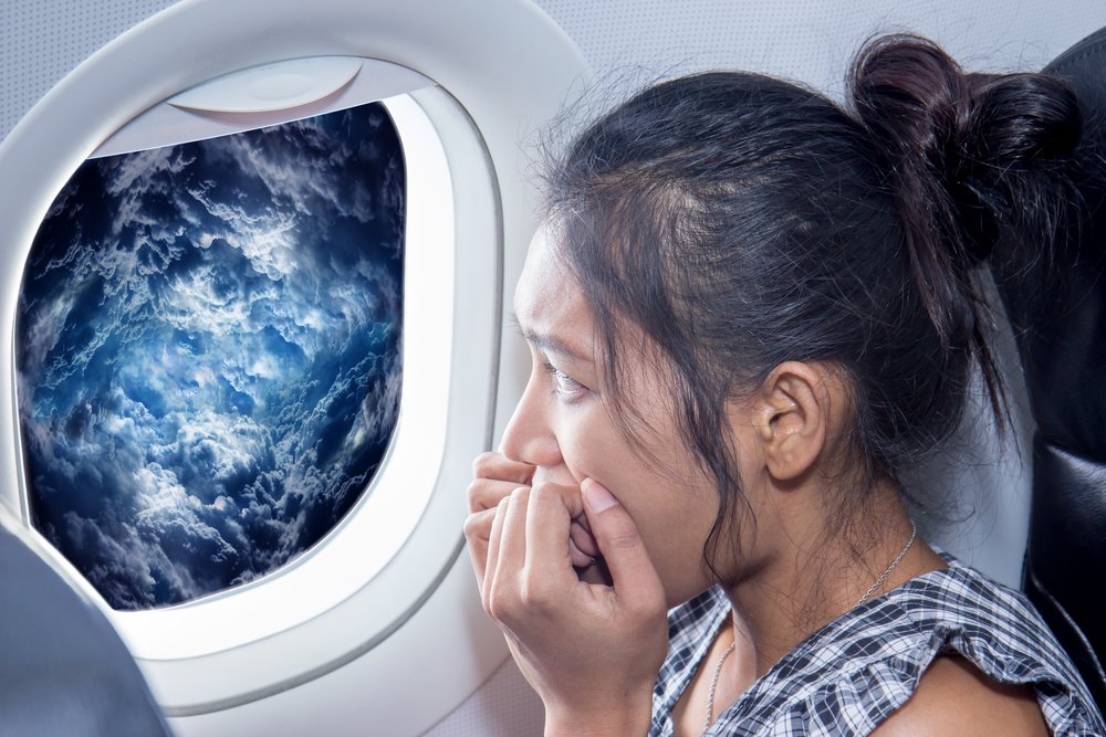 Scared mulher olha para as nuvens de uma janela de avião Viajante olhando pela janela do avião em uma tempestade raging. O passageiro tem medo de um acidente de avião. Mulher nos aviões que olham nuvens de tempestade.