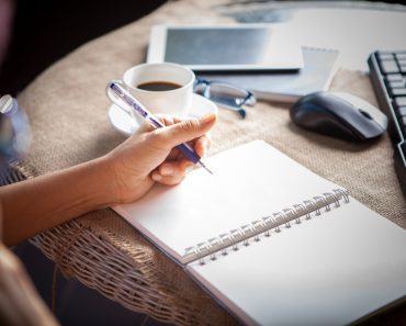 Woman left hand writing on paper book ,on table shot