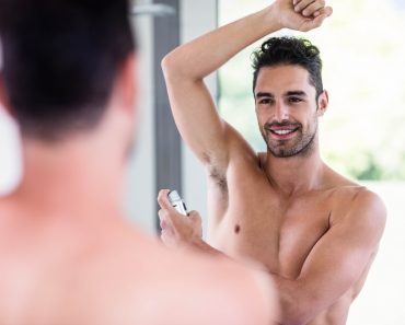 Handsome shirtless man putting deodorant in the bathroom