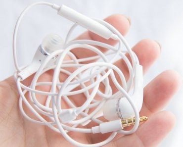 Woman's hand holds white tangled headphones isolated over white background (zazdravnaya)(s)