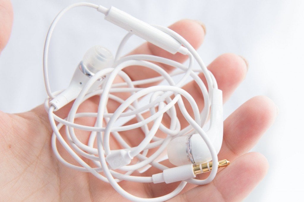 Woman's hand holds white tangled headphones isolated over white background (zazdravnaya)(s)