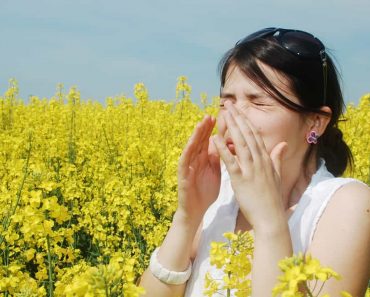 Pollen allergy, girl sneezing in a field of flowers sick