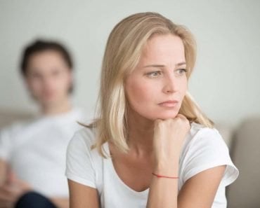 Serious sad woman thinking over a problem, man sitting aside, end of long-term relations, an alcoholic, drug addicted partner, poor conflict management skill, ongoing disagreements with adult son