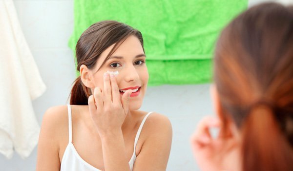 Girl applying lotion on face