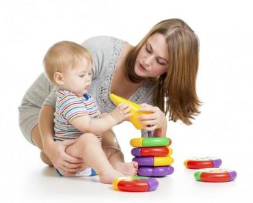 baby boy and mother playing together with construction set toy handing toy to mother