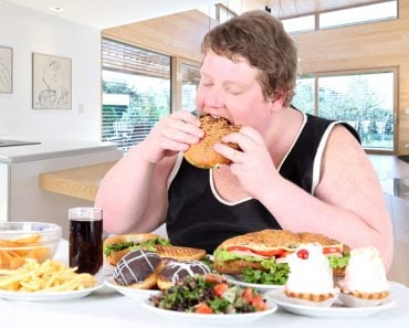 Fat man overeating food of full table