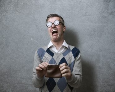 Broke man with thick glasses holding an empty purse and crying, poverty and debts concept - Image(Stock-Asso)s