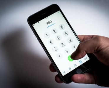 London, LondonUK - April 02 2019 iPhone being used to dial emergency phone numbers, 999, 911, 112 white background with mans hand holding mobile or cell phone - Image( Simon Vayro)S