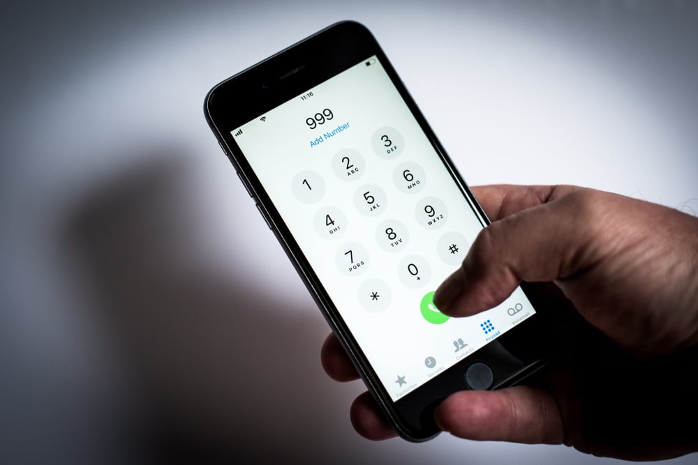 London, LondonUK - April 02 2019 iPhone being used to dial emergency phone numbers, 999, 911, 112 white background with mans hand holding mobile or cell phone - Image( Simon Vayro)S