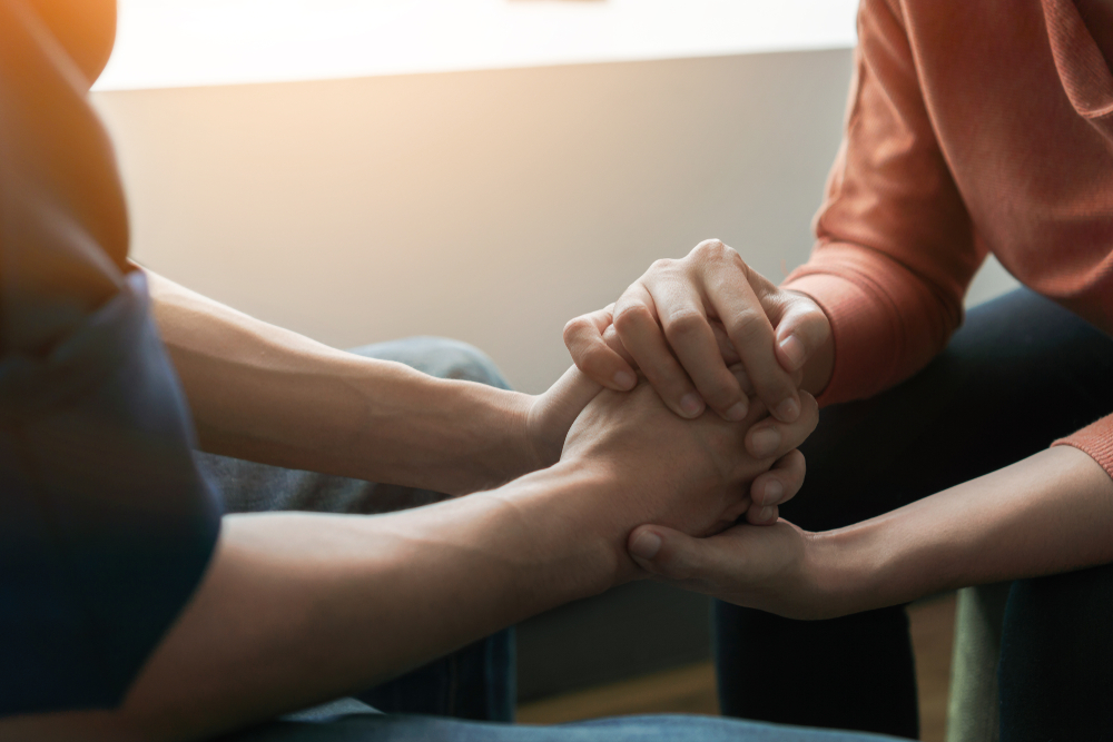 PTSD Mental health concept, Psychologist sitting and touch hand young depressed asian man for encouragement near window with low light environment.Selective focus. - Image( Chanintorn.v)s