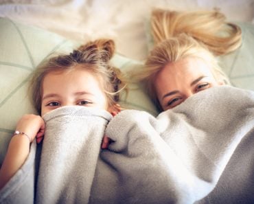 Portrait mother and daughter hide under blanket on a bed. - Image(Liderina)s