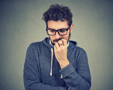 Closeup portrait nervous man biting fingernails craving something and anxious on gray wall background. Negative human emotion facial expression perception - Image(pathdoc)s