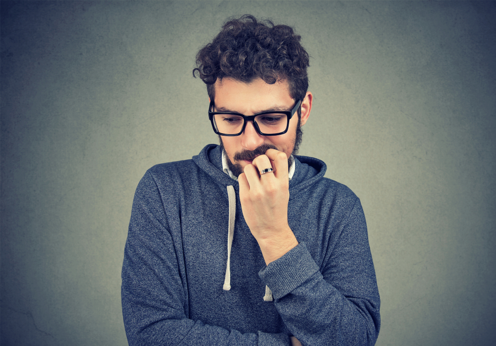 Closeup portrait nervous man biting fingernails craving something and anxious on gray wall background. Negative human emotion facial expression perception - Image(pathdoc)s