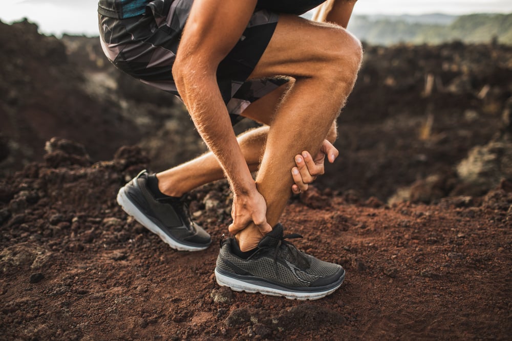 Achilles injury on running outdoors. Man holding Achilles tendon by hands close-up and suffering with pain( Breslavtsev Oleg)s