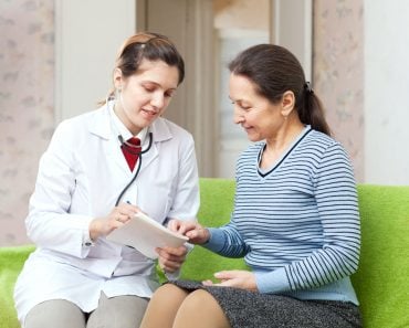 friendly doctor examining mature woman on couch at home - Image( Iakov Filimonov)s