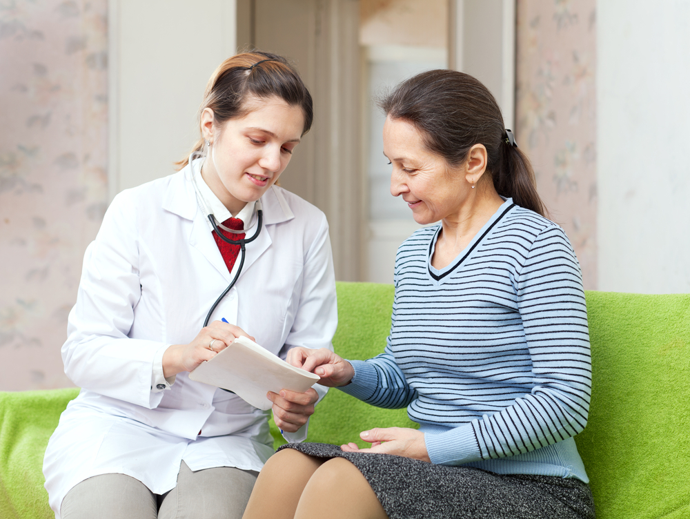 friendly doctor examining mature woman on couch at home - Image( Iakov Filimonov)s