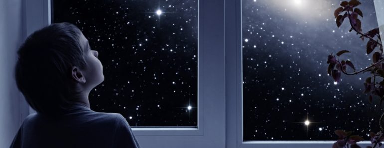 A little boy is standing near the window and looking outside( Yuriy Mazur)s