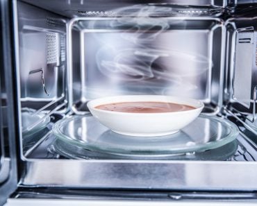 Inside view of new clean staniless microwave oven with a tomato soup in white plate( Marian Weyo)s
