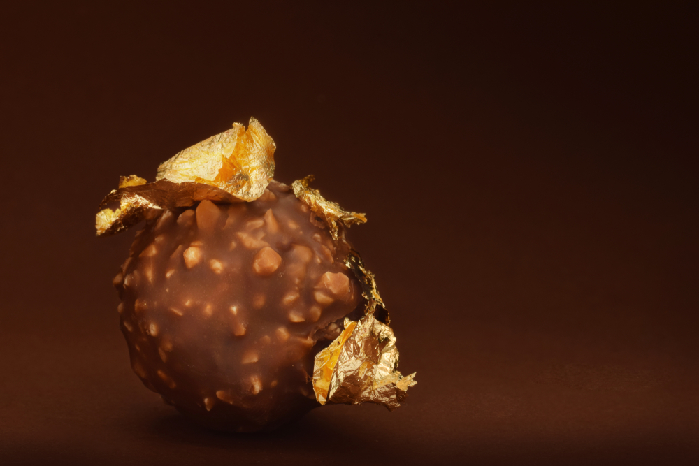 Chocolate praline with edible gold on brown dark background low key(igra.design)s