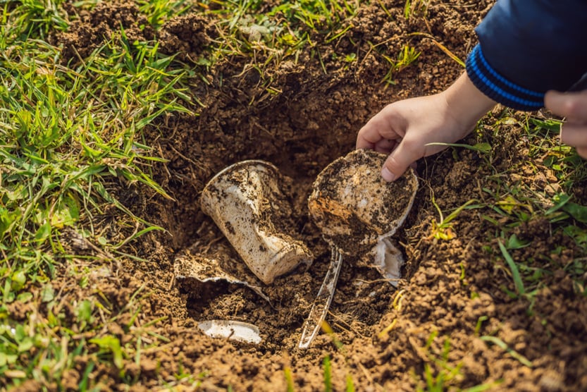 The boy plays recycling. He buries plastic disposable dishes and biodegradable dishes(Elizaveta Galitckaia)s