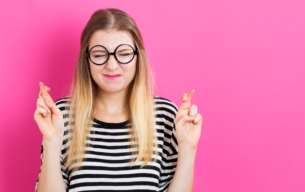 Young woman crossing her fingers and wishing for good luck(TierneyMJ)s