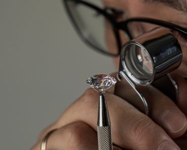 Man jeweller examines polished diamond through magnifier(EgolenaHK)s