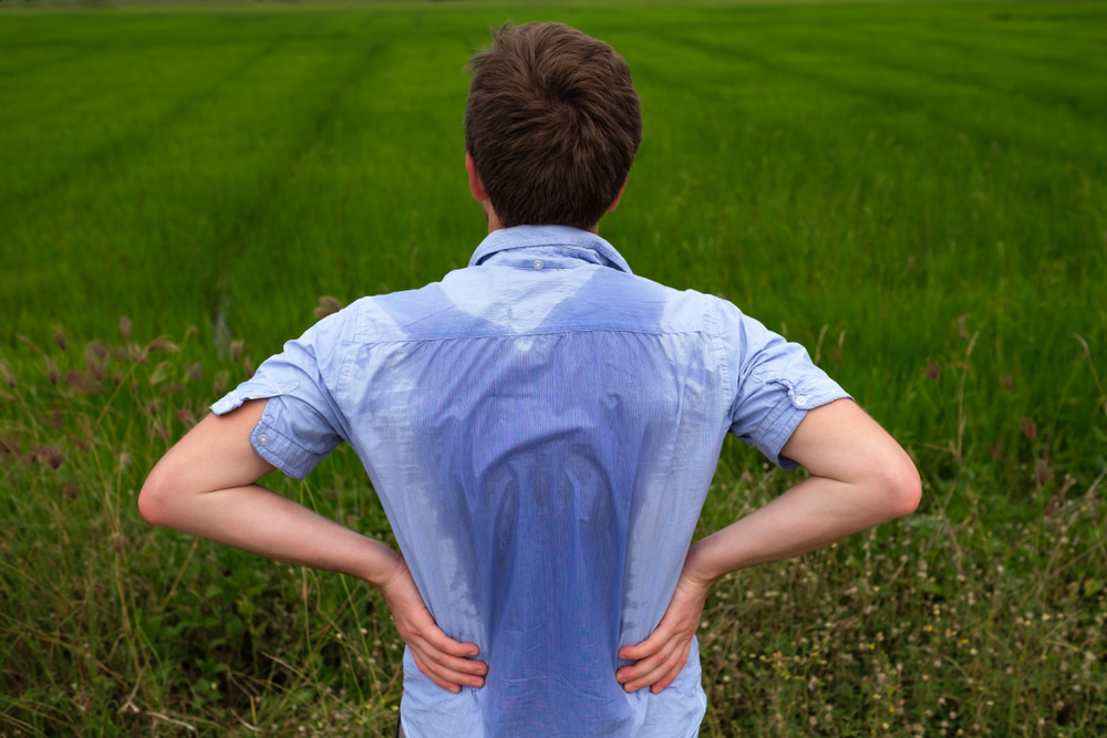 Man with hyperhidrosis sweating very badly under armpit in blue shirt because of hot weather(Koldunova Anna)s