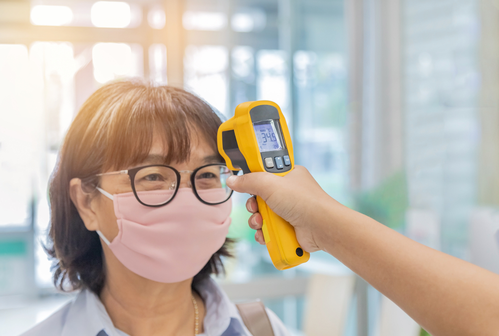 Security guard using digital medical electronic thermometer measures checking body temperature screening passengers(Soonthorn Wongsaita)s