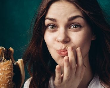 Woman eating a hamburger, chewing a hamburger, hamburger in hand(ViChizh)s