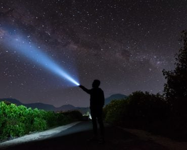 An amazing milky way and stargazing with a silhouette man flashing the light towards the stars(yusuf madi)S