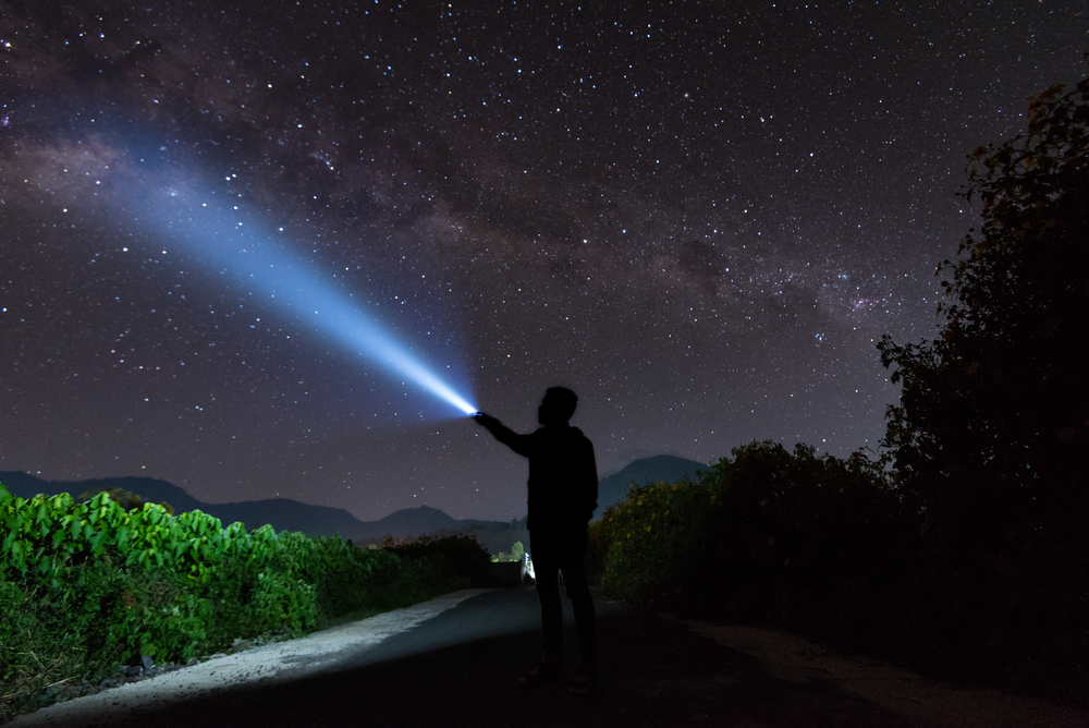 An amazing milky way and stargazing with a silhouette man flashing the light towards the stars(yusuf madi)S