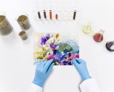 Scientist with a magnifying glass taking a look at a painting