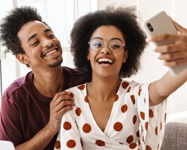 Happy couple taking a selfie together on the couch at home