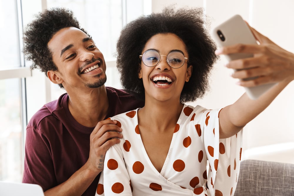 Happy couple taking a selfie together on the couch at home