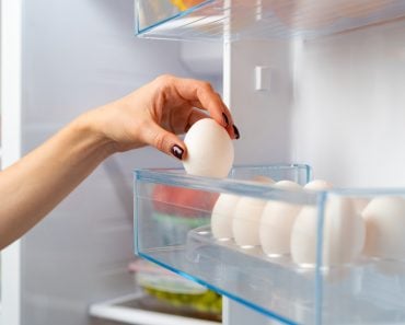 Female hand taking egg from a fridge close up