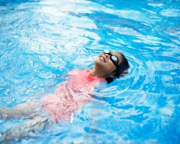 Young,Asian,Child,With,Peach,Swimwear,Floating,In,Pool.swimming,Lesson.