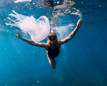 Woman,Underwater,With,Jellyfish,In,Blue,Ocean.,Lady,Glides,Underwater