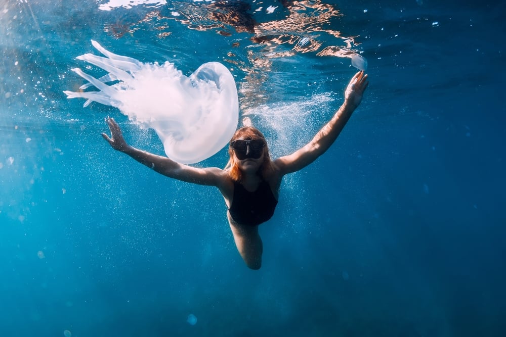 Woman,Underwater,With,Jellyfish,In,Blue,Ocean.,Lady,Glides,Underwater