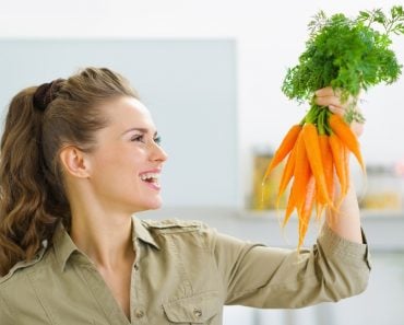 Happy,Young,Housewife,Holding,Carrots,In,Kitchen