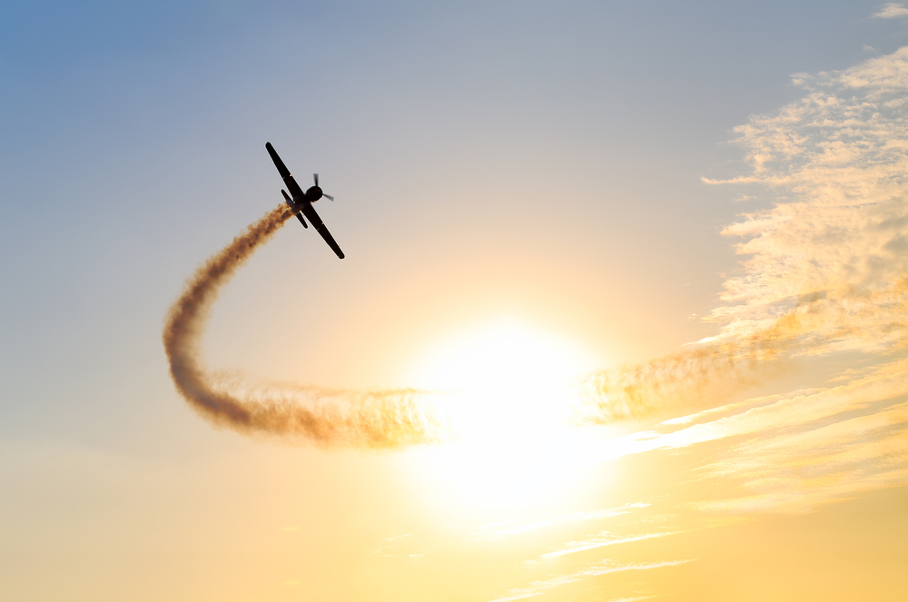 Silhouette,Of,An,Airplane,Performing,Acrobatic,Flight,At,Sundown.,Trace