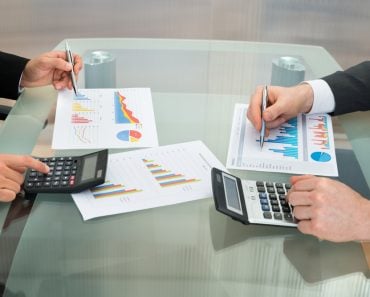 Close-up,Of,Two,Businessmen,Analyzing,The,Graph,Using,Calculator,On