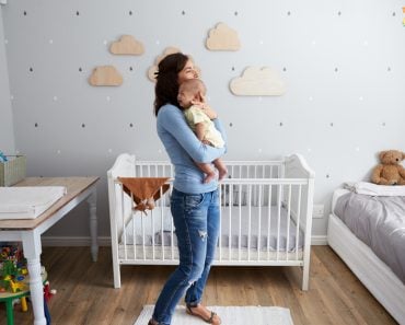 Mother Comforting Newborn Baby Son In Nursery