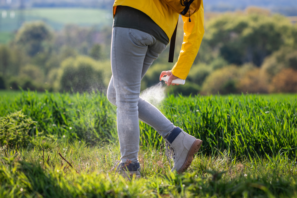 Woman,Hiker,Spraying,Insect,Repellent,Against,Tick,On,Her,Legs