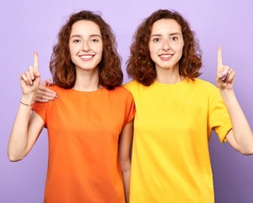 Happy,Beautiful,Twins,Girls,Point,Up,Isolated,On,Blue,Background,