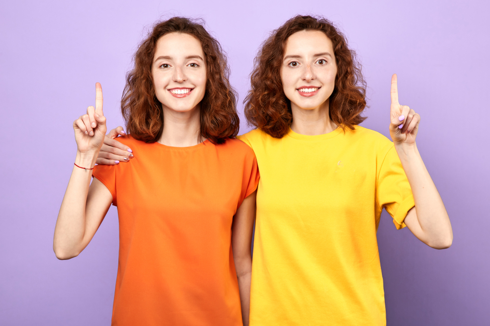 Happy,Beautiful,Twins,Girls,Point,Up,Isolated,On,Blue,Background,